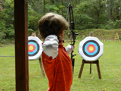 Kid aiming at target with bow and arrow