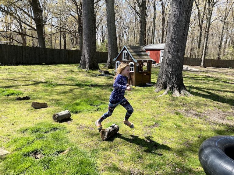child jumping over logs