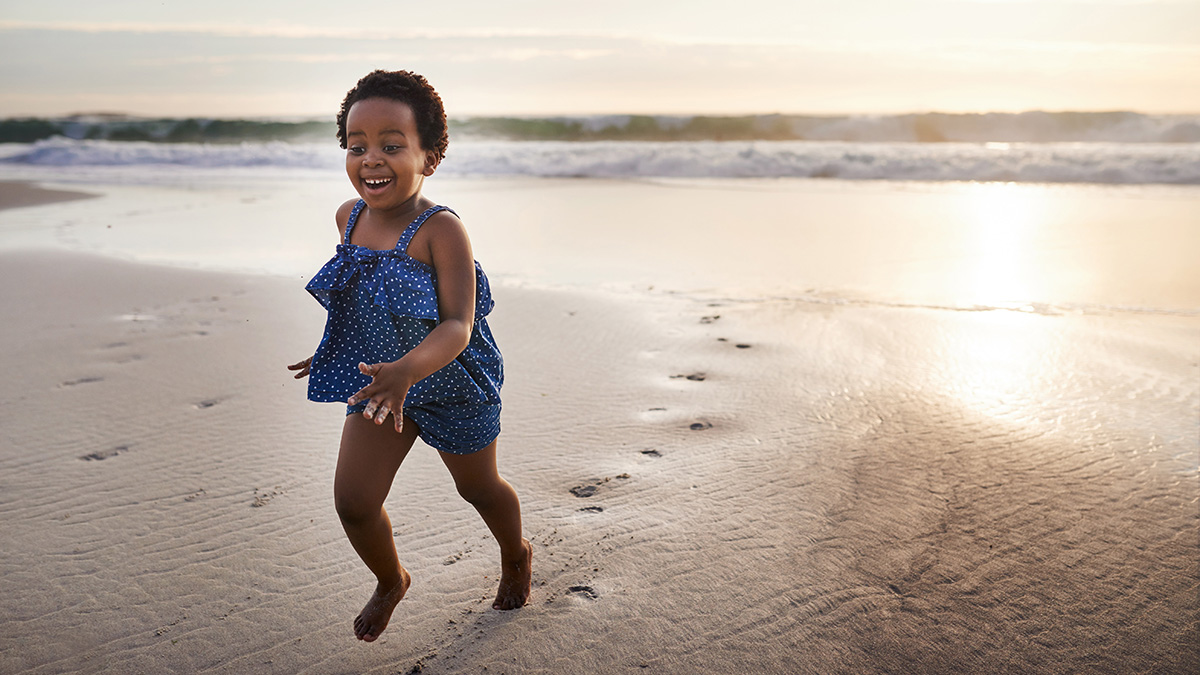 Shot of an adorable little girl having fun on the beach at sunset