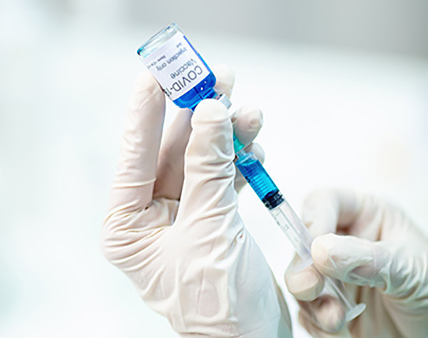 Close-up of hands with protective gloves fills syringe with vaccine, doctor holds Coronavirus Covid-19 vaccine glass vial, filling syringe from medicine vial