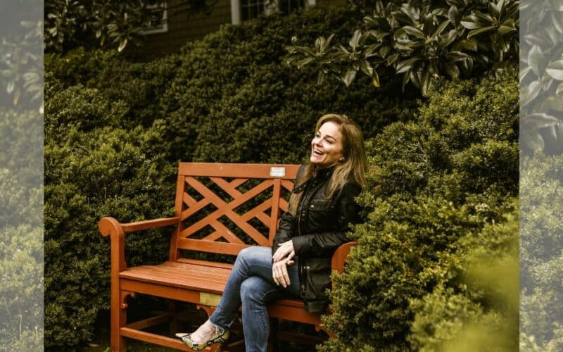 Diana Love sitting on a bench surrounded by trees.