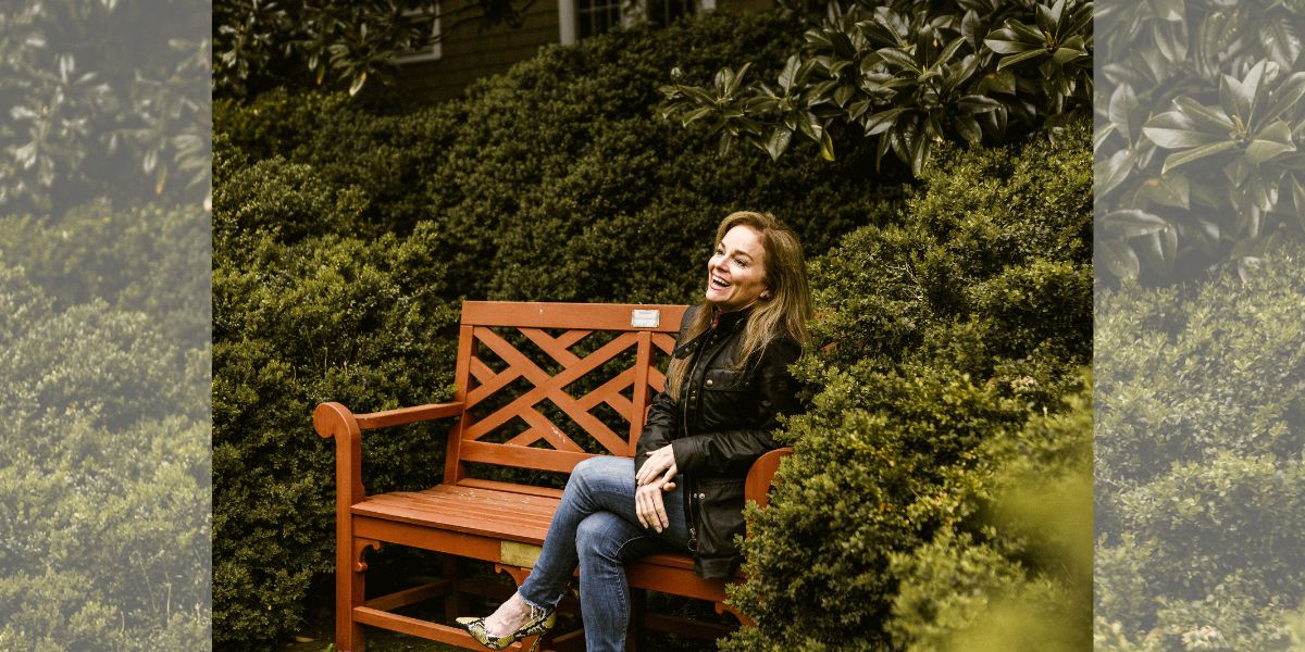 Diana Love sitting on a bench surrounded by trees.
